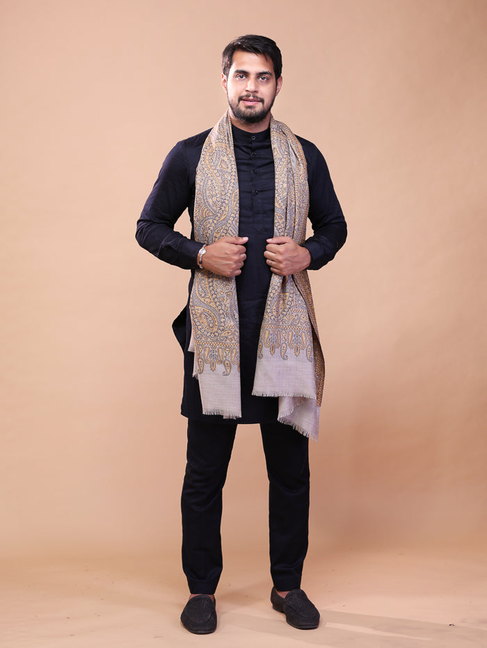 Man wearing a patterned scarf and black outfit against a beige background